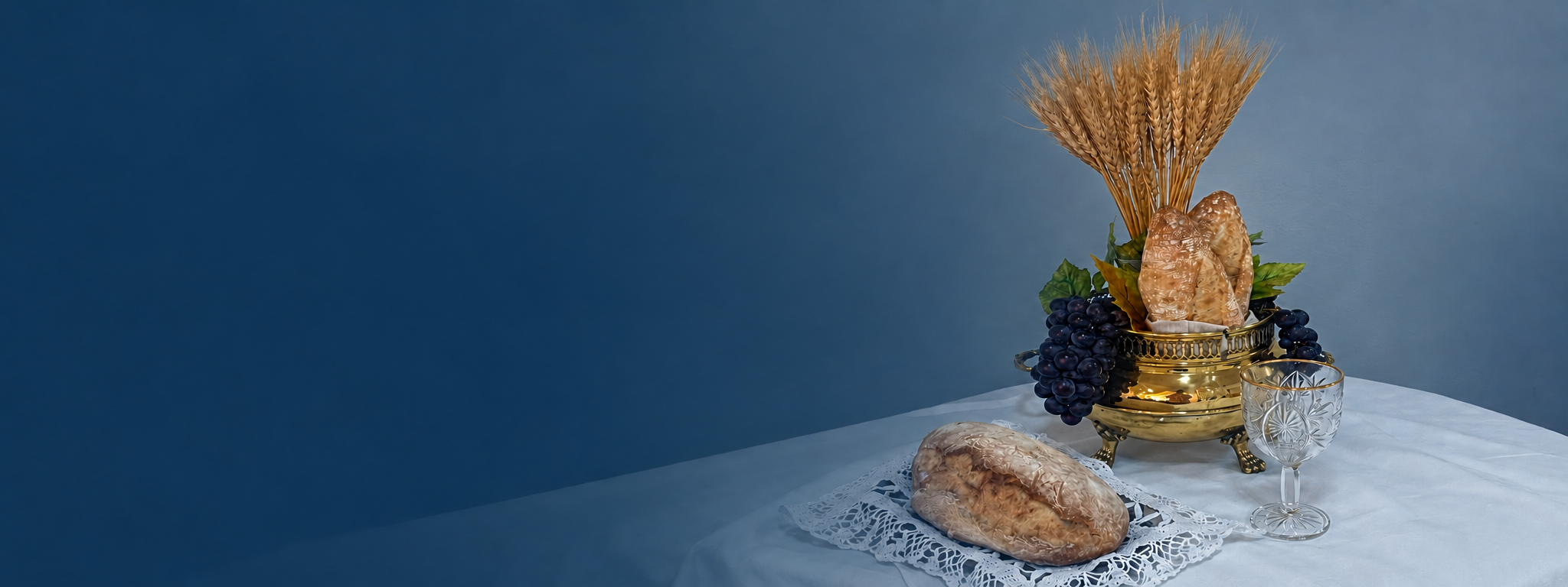 Mesa com p&atilde;o, uvas e c&aacute;lice preparada para a ceia